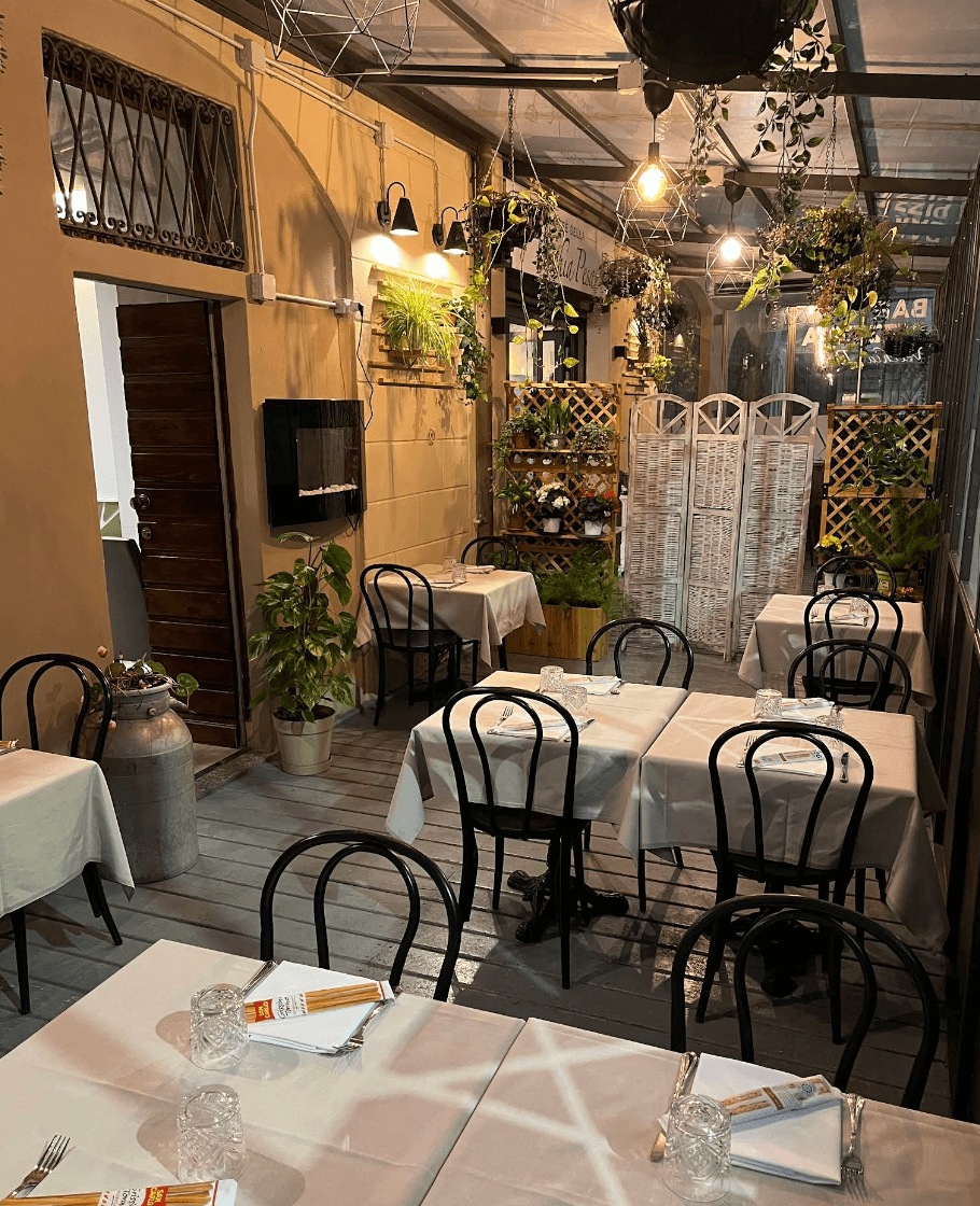 Veranda interna della Vecchia Pesa con tavoli apparecchiati e piante